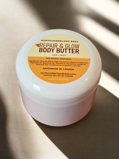 A container of Northumberland Bees Repair & Glow Body Butter with the label facing up. The label includes the product name, brand, and a claim of being handmade in Canada.