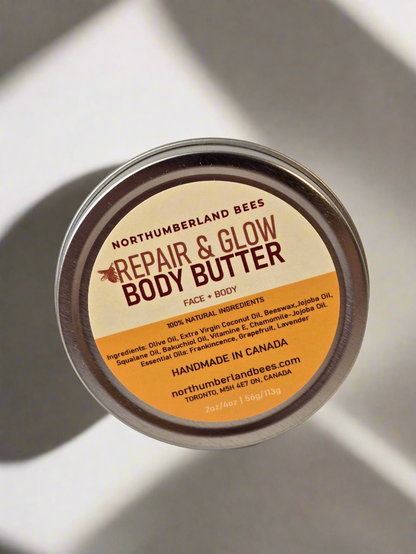 A container of Northumberland Bees Repair & Glow Body Butter with the label facing up. The label includes the product name, brand, and a claim of being handmade in Canada.