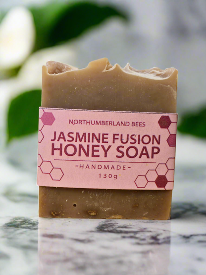A bar of Jasmine Fusion Honey Soap with a label that includes the brand name and product name, handmade, and weight of 130g.