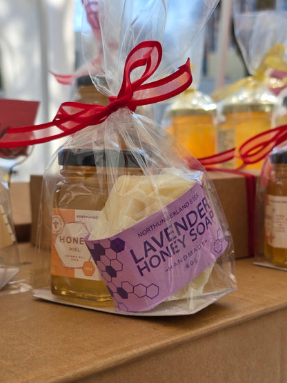 Lavender honey soap and jar with a red ribbon on a table.