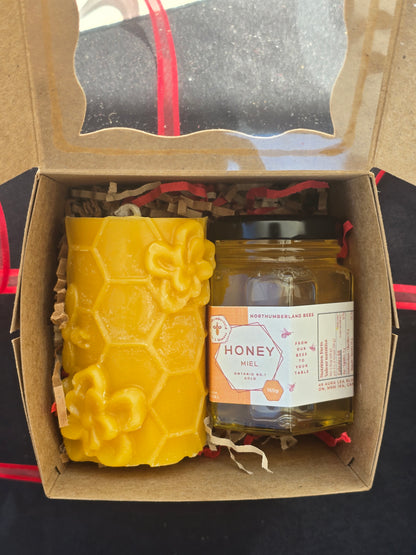 Honeycomb-shaped product and jar of honey in a cardboard box with visible brand label.